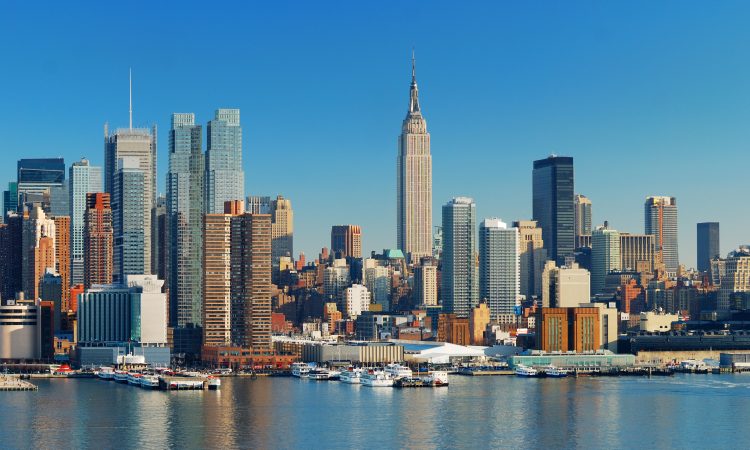 Manhattan Skyline with Empire State Building, New York City over Hudson River with boat and pier.