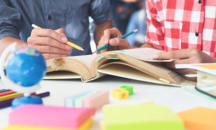 Young woman and man studying for a test or an exam. Tutor books with friends. Young students campus helps friend catching up and learning. People, learning, education and school concept.