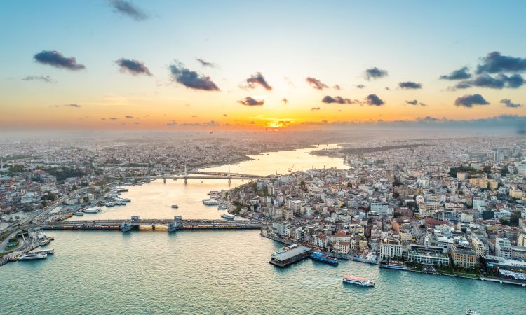Aerial drone view of Istanbul at sunset, Turkey. Multiple residential buildings, mosques, Galata and Metro bridges over the Golden Horn waterway with floating ships