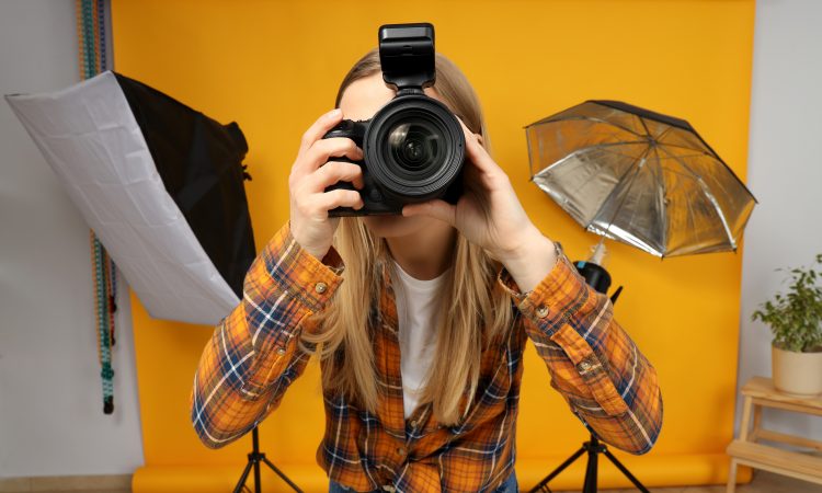 Beautiful girl photographer in the photo studio, on a yellow background.