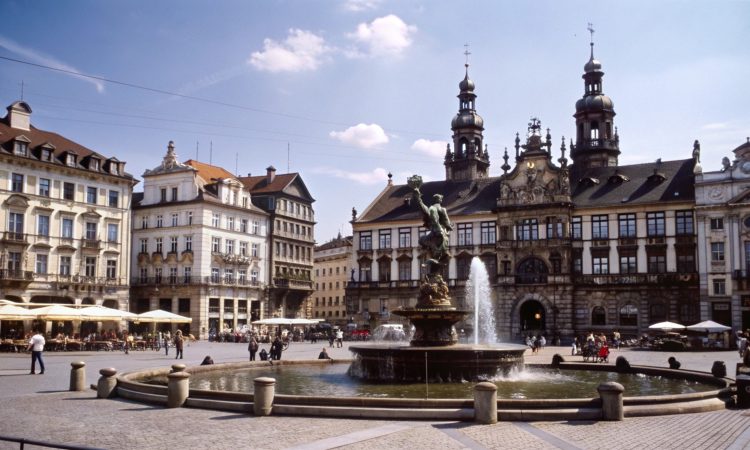 Fountain in European city square with historic buildings.