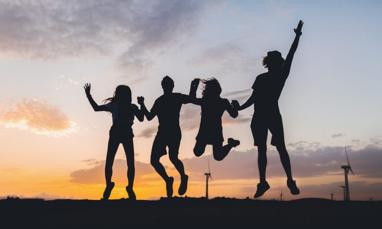 happy hipster friends company silhouettes on sunset nature landscape jumping together holding hands having fun on vacation in desert safari, young people traveling enjoying life and freedom