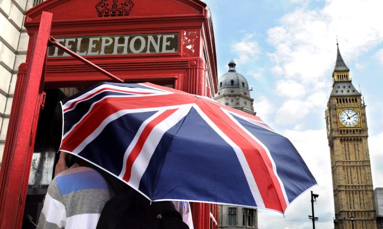 Tourist with British umbrella in telephone box and Big Ben in London